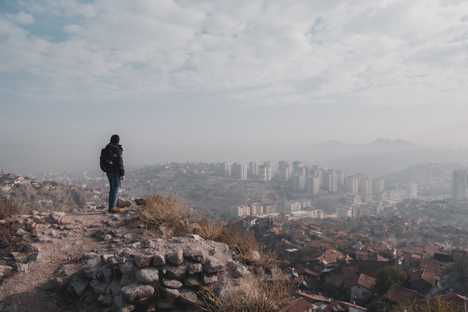 man standing on top of hill overlooking city